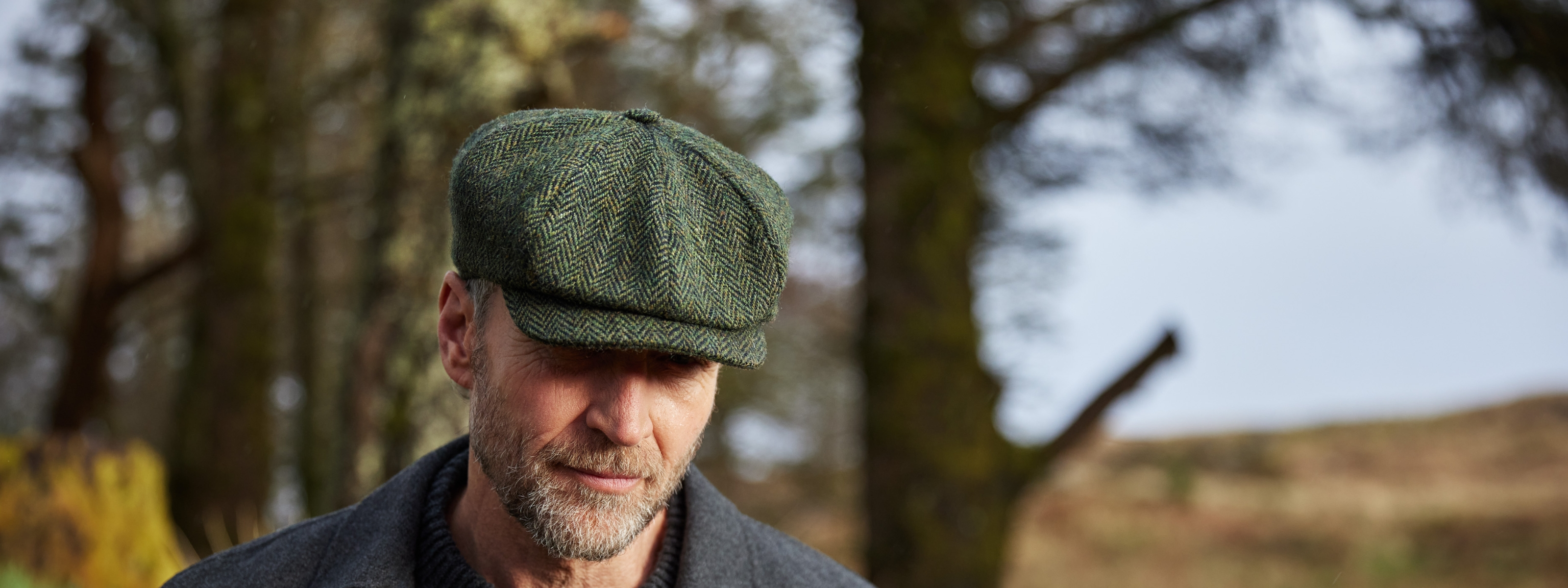 Finn wearing green herringbone tweed Newsboy Cap in a Irish forest