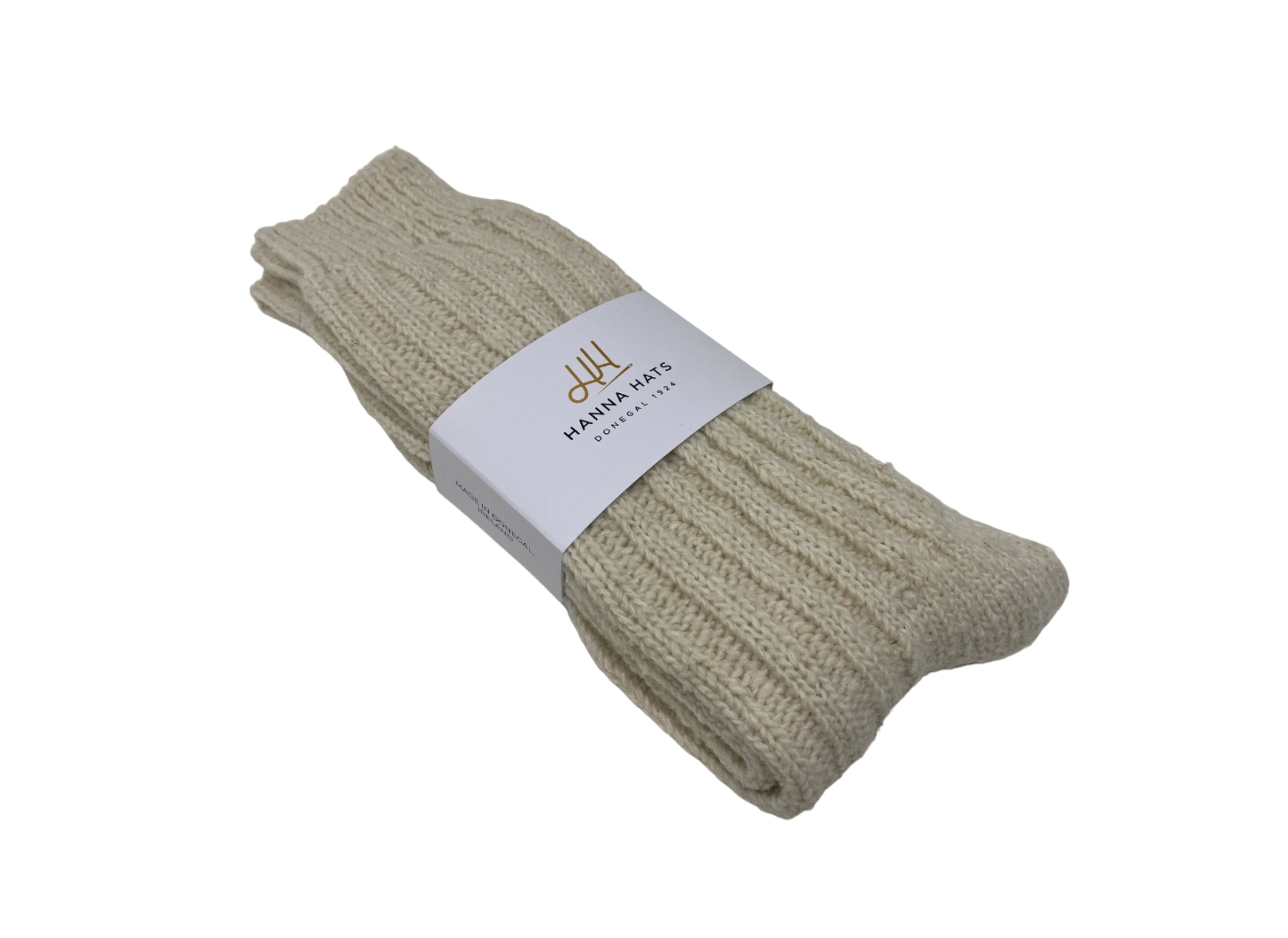 A pair of cream-colored Donegal Socks by Hanna Hats, chunky ribbed wool, folded with a white Hanna Hats label, displayed on a white background.