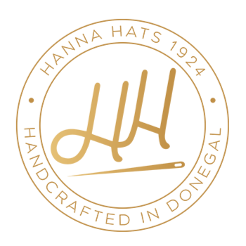 A circular gold logo with stylized overlapping “HH” above a sewing needle in the center. Text around the circle reads “HANNA HATS 1924” on top and “HANDCRAFTED IN DONEGAL” on the bottom.