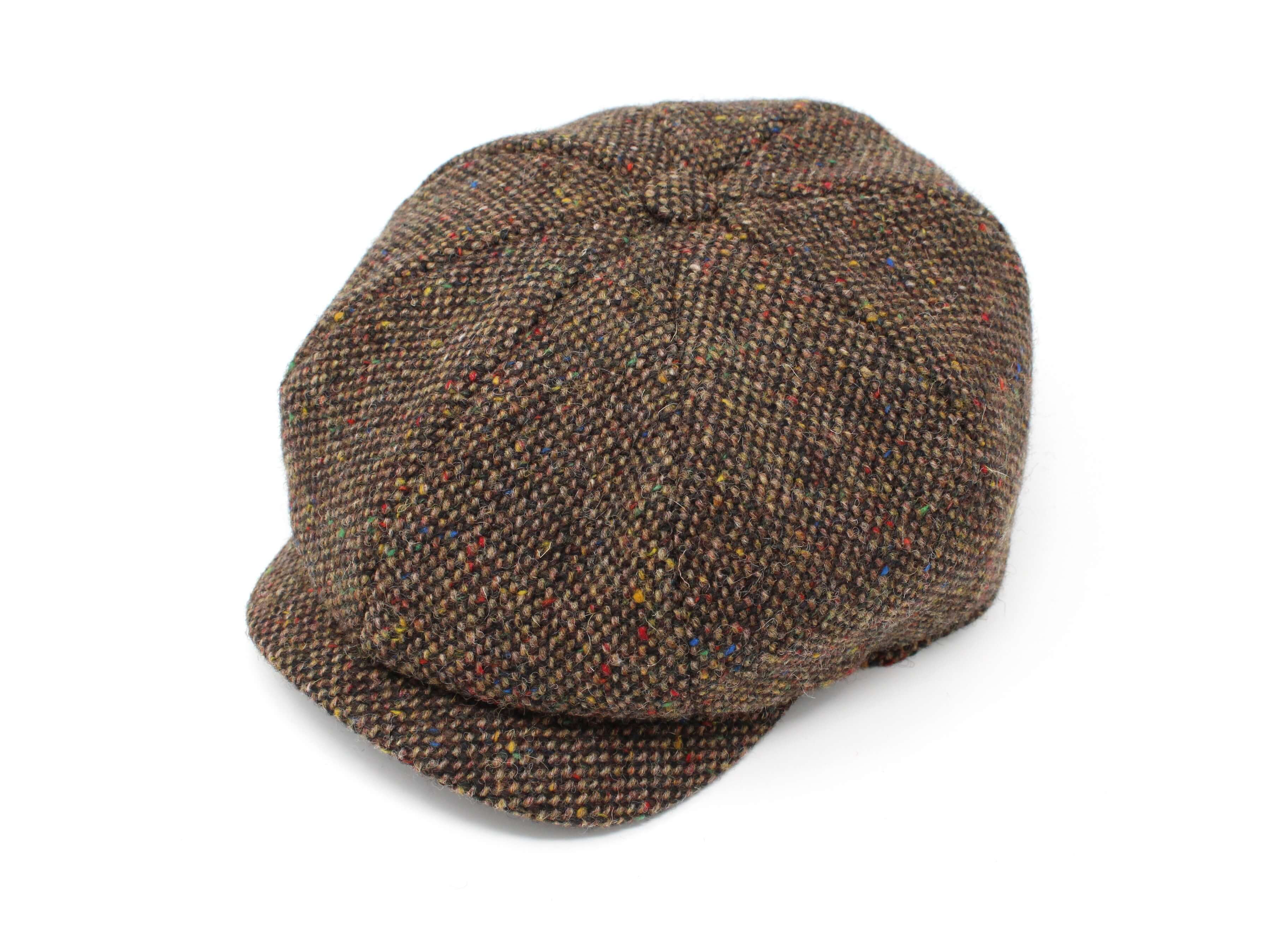 The Hanna Hats JP Cap Tweed is a brown newsboy cap featuring a subtle check pattern and multicolored specks, designed for a perfect fit and displayed on a white background.