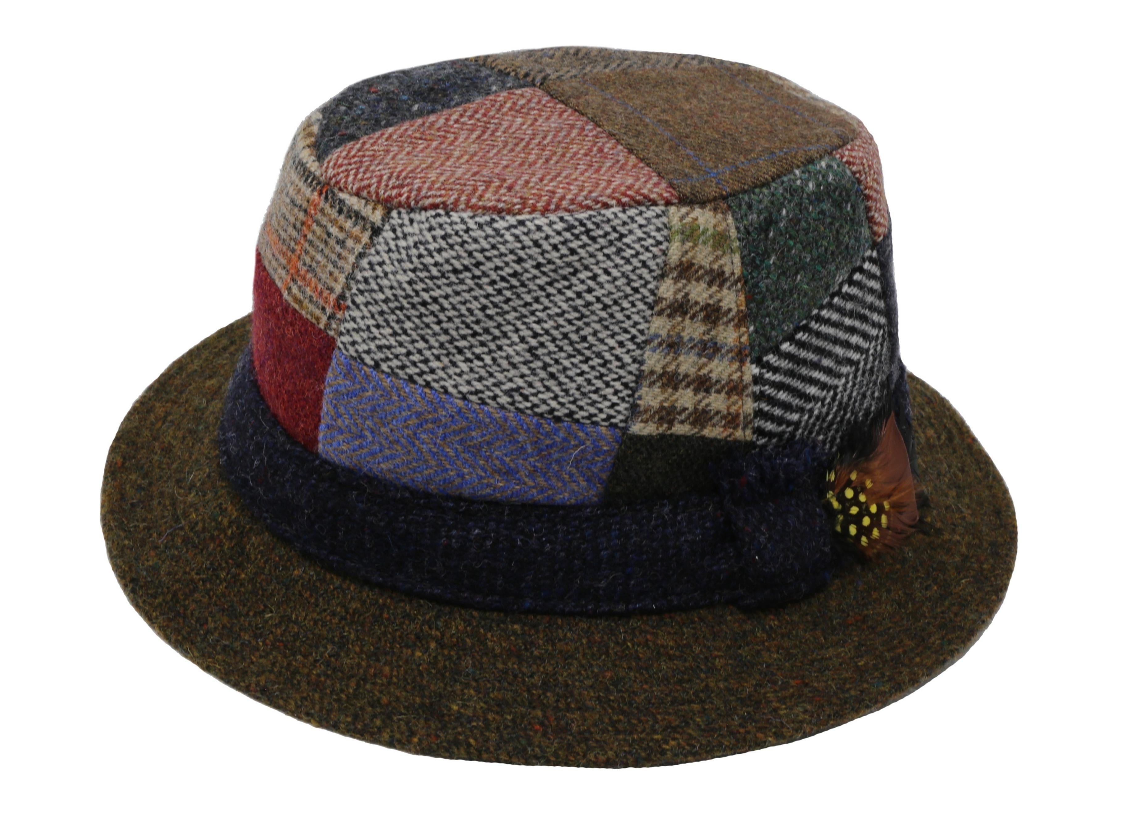 The Walking Hat Patchwork Tweed by Hanna Hats is a wool hat inspired by Donegal heritage, featuring colorful tweed fabrics, a dark brim, and a brown decorative feather.
