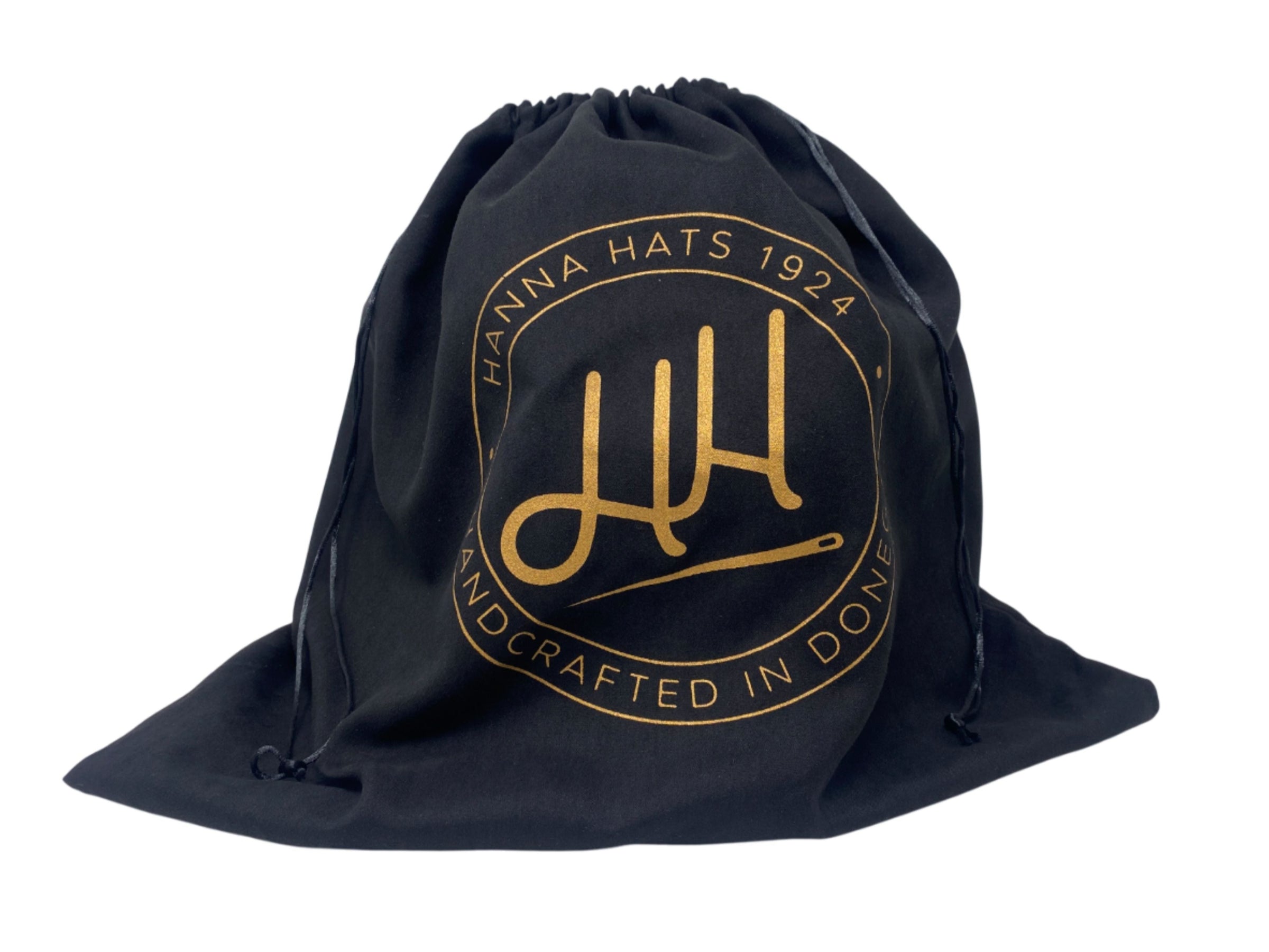 The Dust Bag by Hanna Hats of Donegal Ltd is black with a gold circular logo, “HANNA HATS 1924 HANDCRAFTED IN DONEGAL,” stylized "HH" initials, and hatpin—ideal for protecting hats and storing caps.