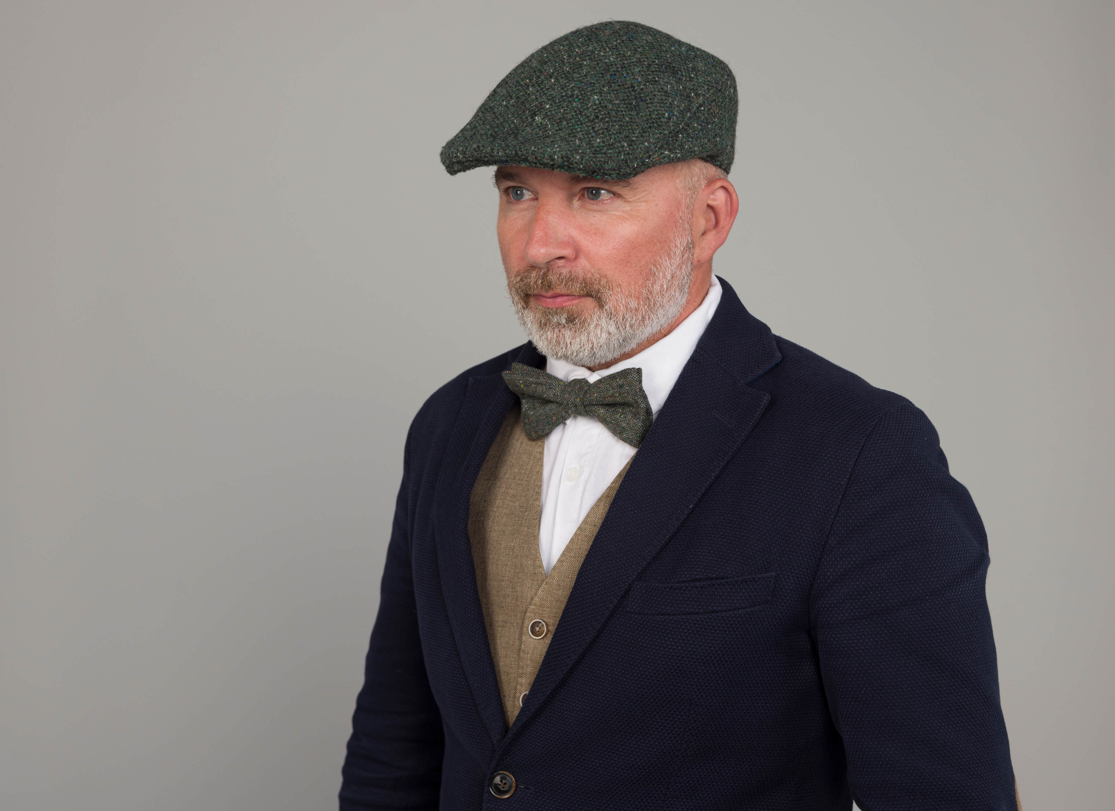 Adam wearing green bow tie tweed with green tweed flat cap and sports jacket