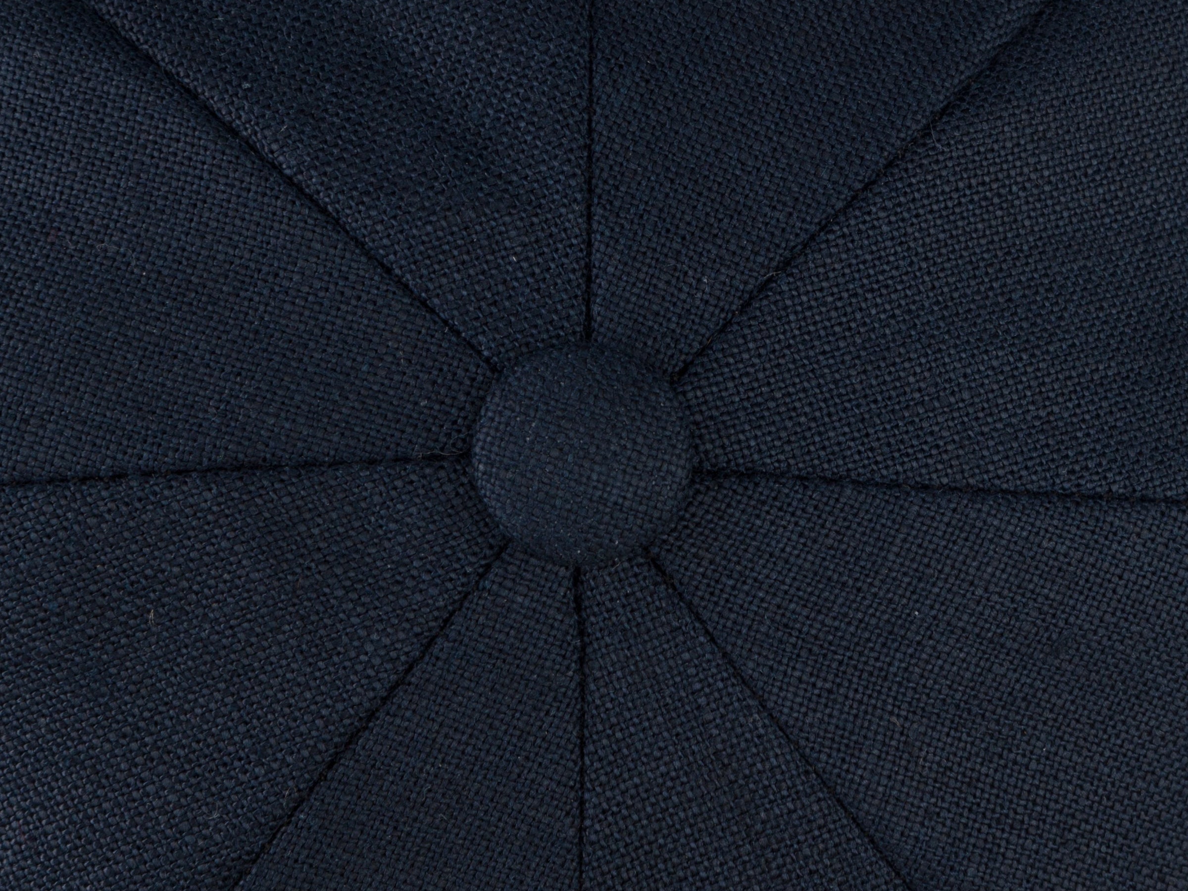 Close-up of the Connery Cap Linen by Hanna Hats, featuring dark fabric with a central sewn button and radiating stitched seams—stylishly crafted from recycled plastic for added sustainability.